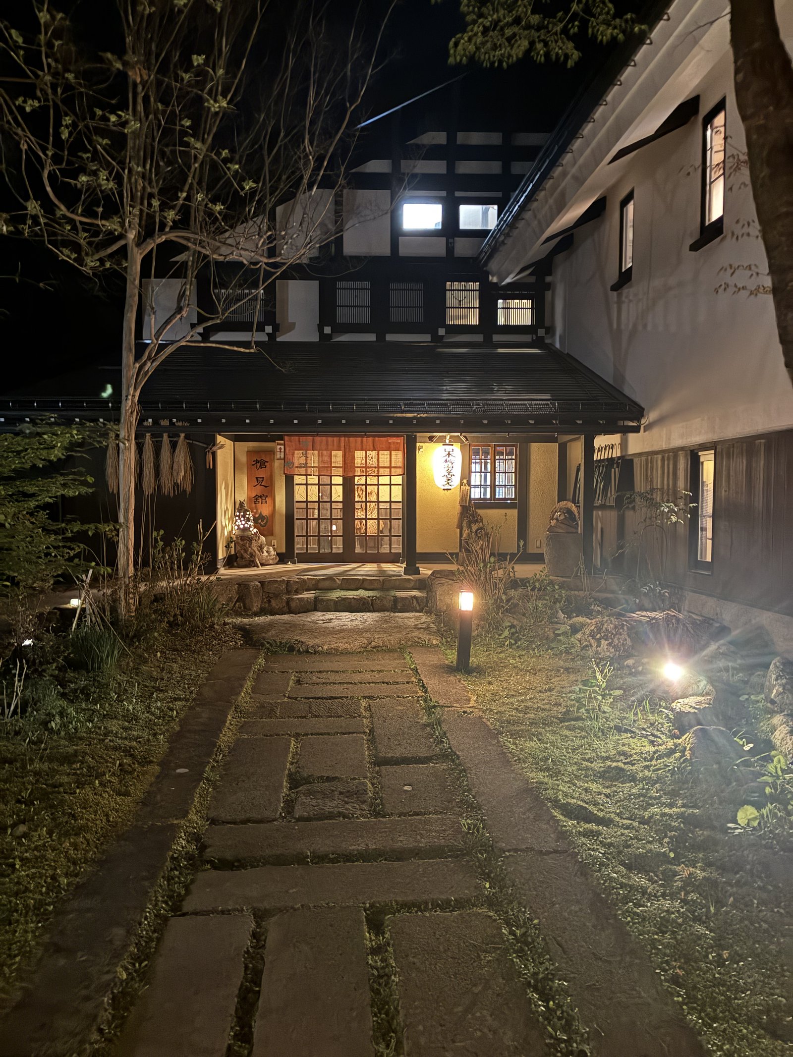Wooden facade of Yarimikan ryokan at night, lit by lanterns in Okuhida Onsen Village