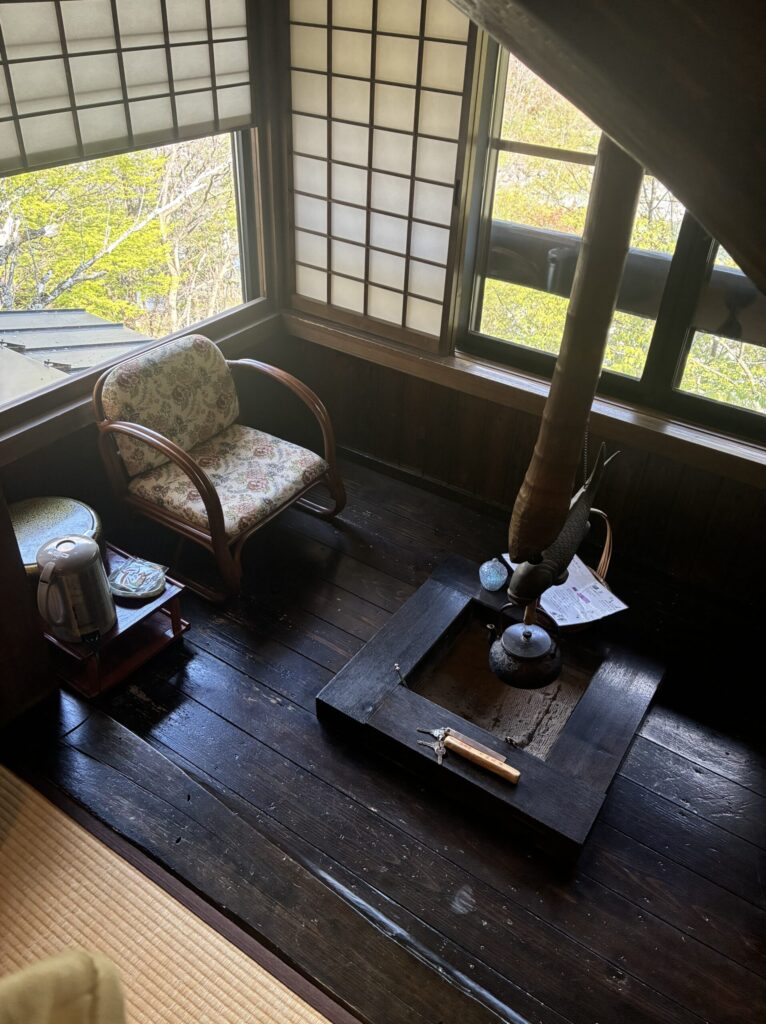 Tatami guest room at Yarimikan with a traditional irori sunken hearth and exposed wooden ceiling beams