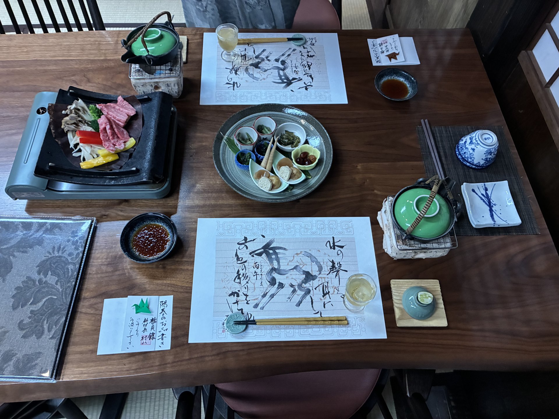 Yoshun spring kaiseki table lineup at Yarimikan with hoba-yaki, hassun plate, calligraphy place mats and aperitif
