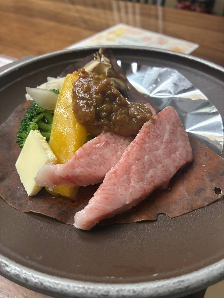 A5-grade Hida wagyu beef cooking on a heated volcanic stone with seasonal vegetables on Night 2 at Yarimikan